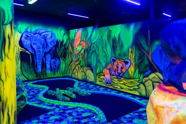 Elefant und Zebra als Wandmalerei über einer Schwarzlichtbahn