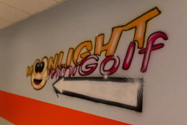Moonlight-Minigolf-Schriftzug an der weißen Wand im Eingangsbereich