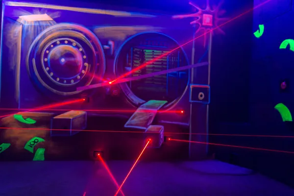 Raum voller roter Laserstrahlen mit Tresorwand als Kulisse