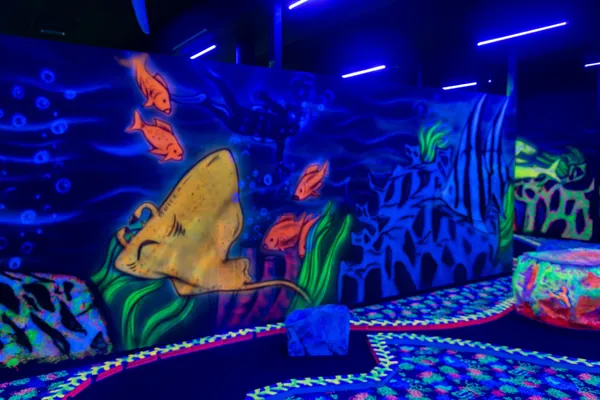 Gelber Fisch und Korallen an der Wand einer blau ausgeleuchteten Bahn